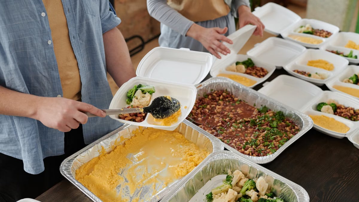 Volunteers preparing food packs indoors for donation.